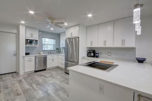 Una cocina moderna con armarios blancos, electrodomésticos de acero inoxidable y una isla central.