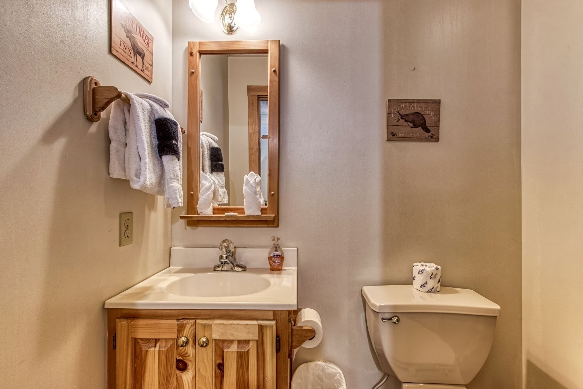 A bathroom with a wooden vanity, a sink, a mirror, a toilet, and a towel rack.