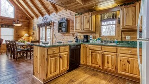 A wooden cabin kitchen with a central island, wooden cabinets, and a built-in dishwasher. - Er6 - On Eagles' Wings - Great Location. Close To All The Action! 6 Bedroom Cabin by RedAwning (Pigeon Forge)