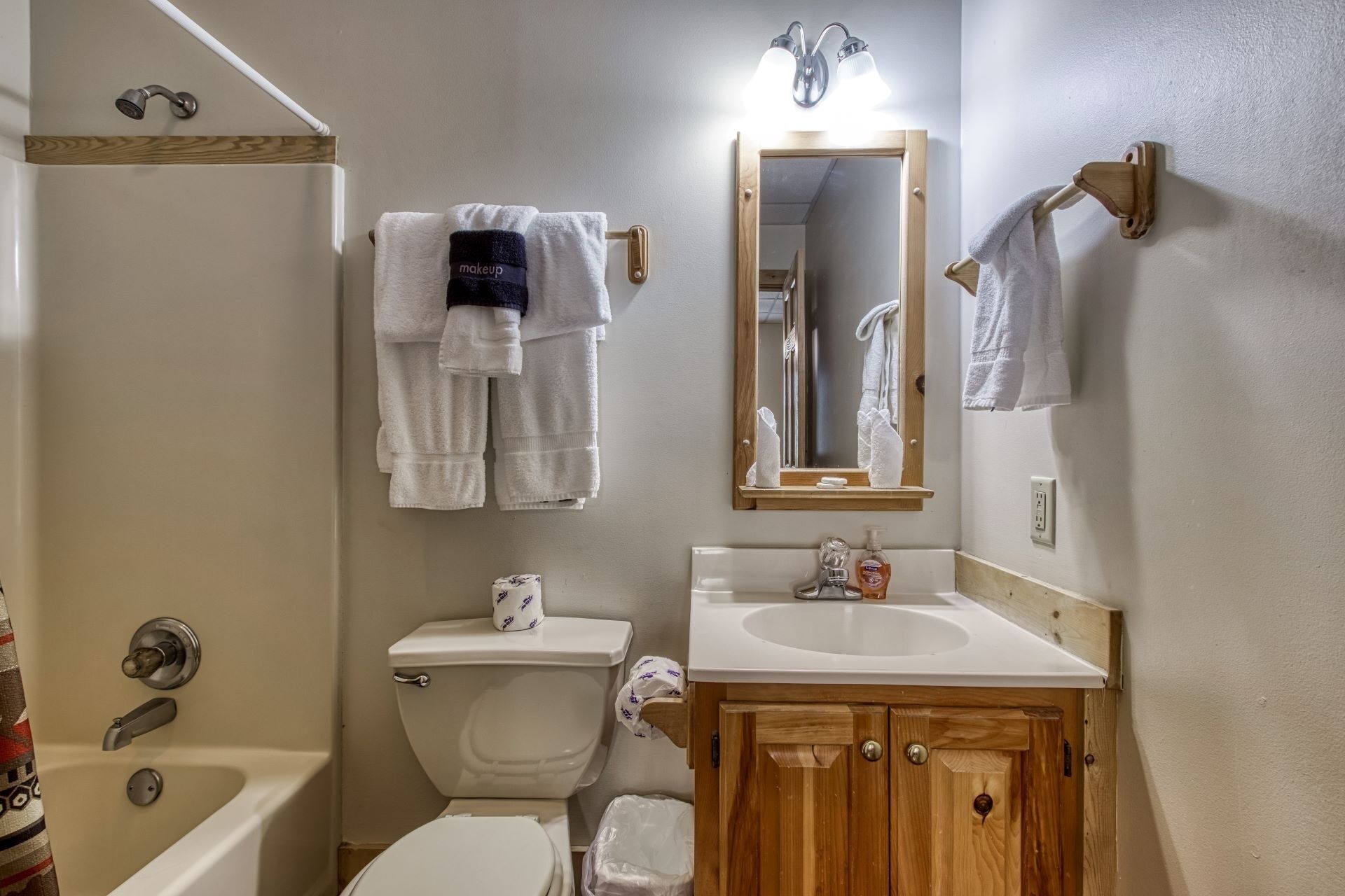 Ein Badezimmer mit Toilette, Waschbecken und Badewanne. Handtücher hängen an einem Wäscheständer und über dem Waschbecken hängt ein Spiegel.