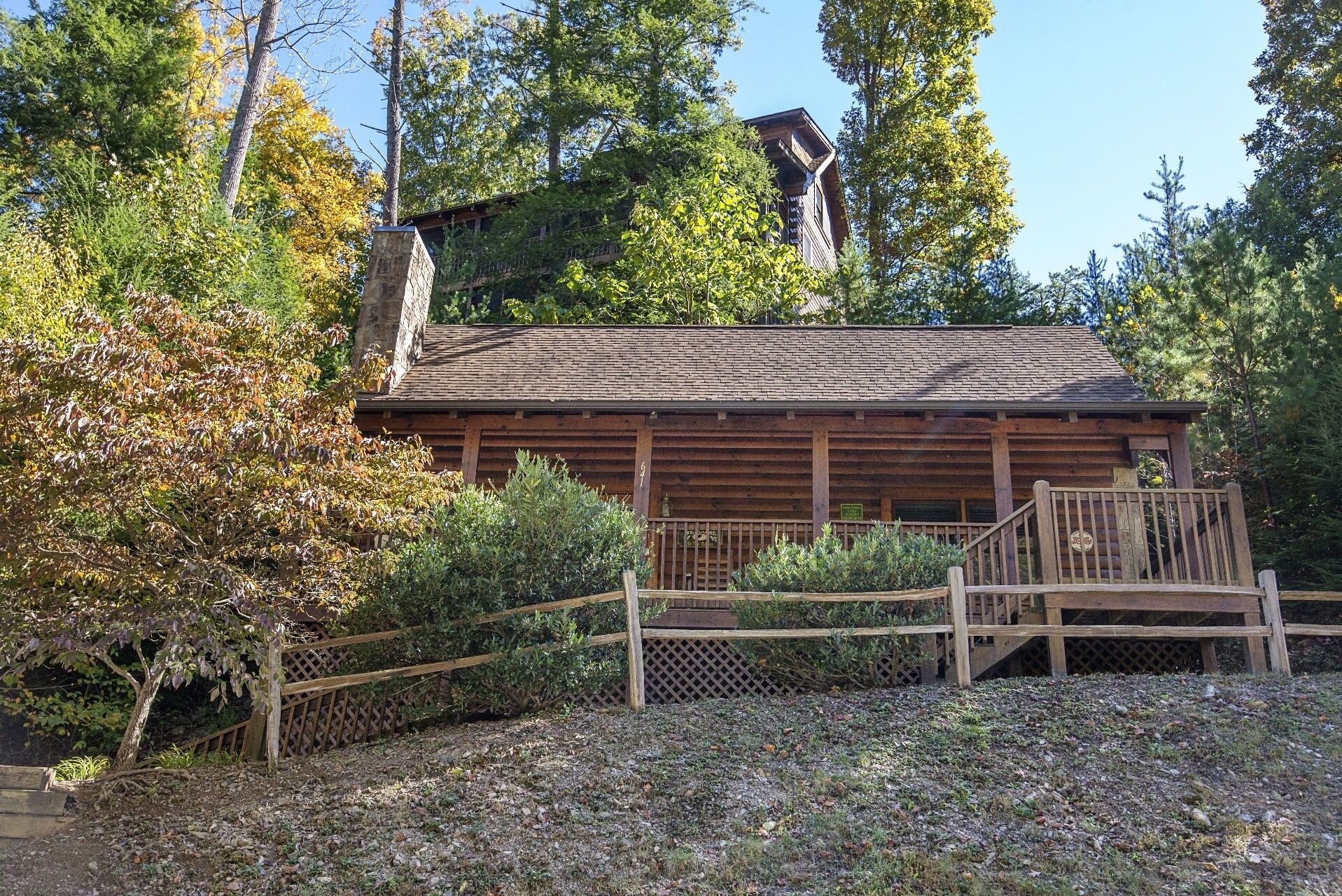 Une cabane rustique en rondins de bois, dotée d’une terrasse en bois et d’une cheminée.