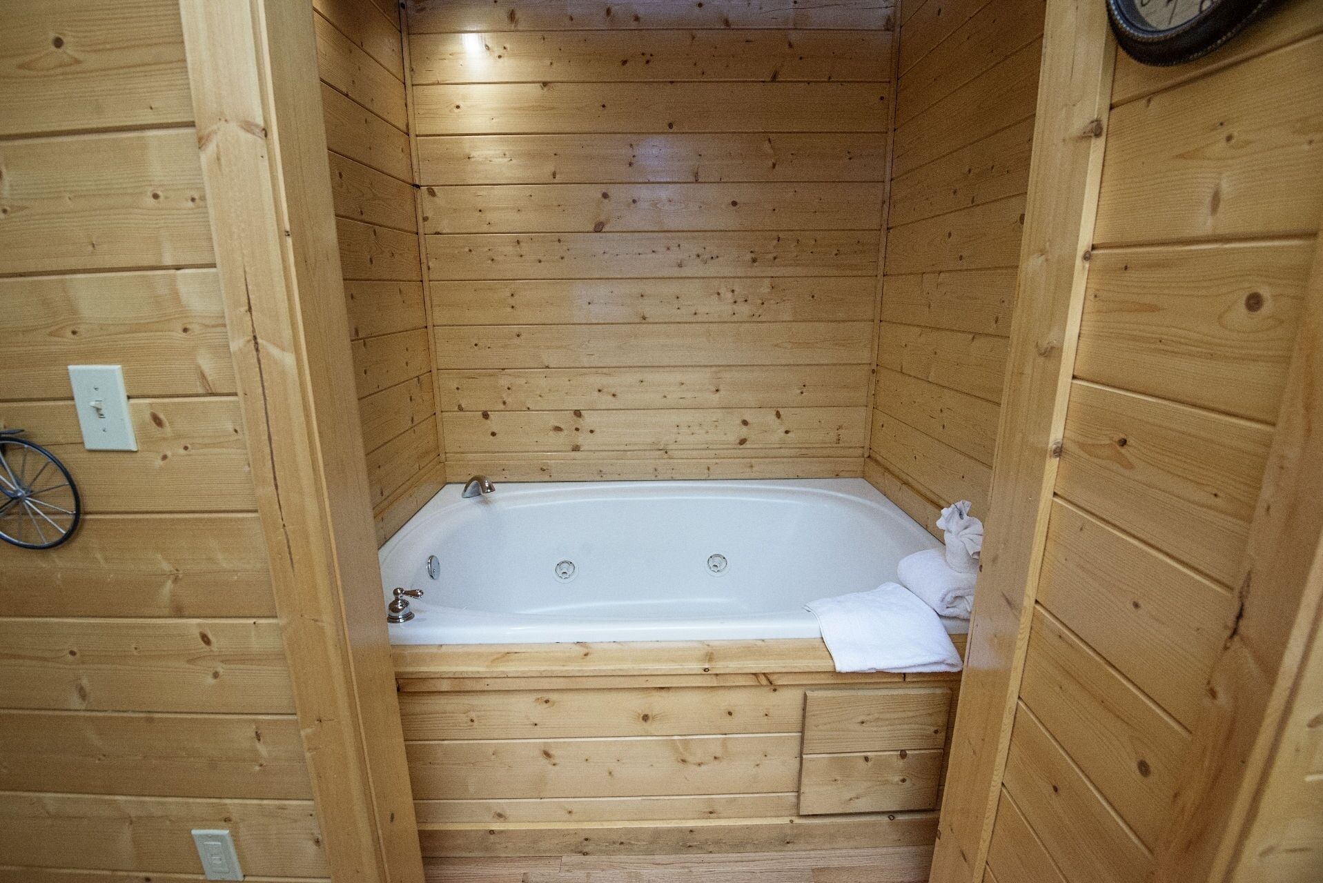 Una cabaña de madera con una bañera integrada, paredes de madera y una bicicleta apoyada contra la pared.