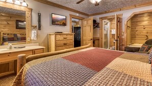 Una habitación acogedora con una cama y cómoda de madera, un ventilador de techo y un televisor en la pared.