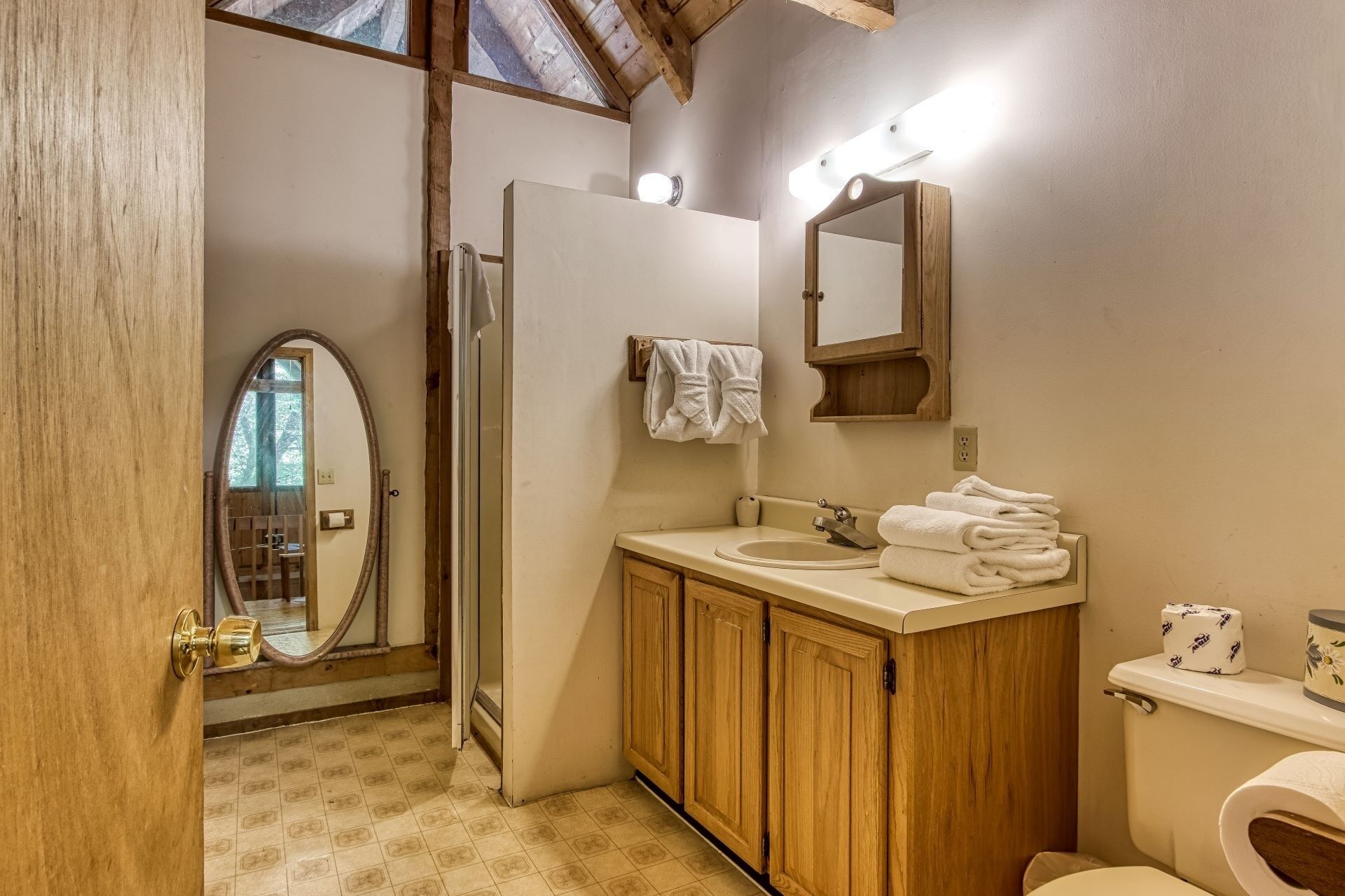 A bathroom with wooden cabinets, a sink, a toilet, and a mirror.