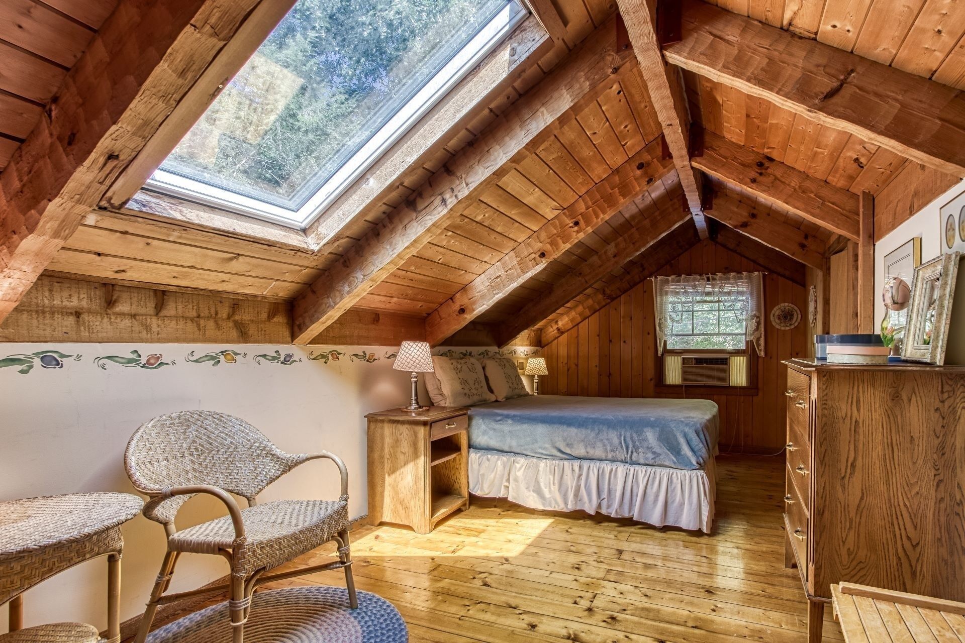 A cozy attic bedroom with a sloped ceiling, a single bed, a chair, and a dresser.