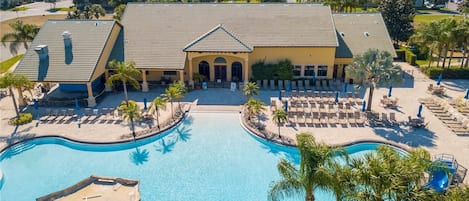 A resort with a large central pool, multiple lounge areas, and a building with a tiled roof.