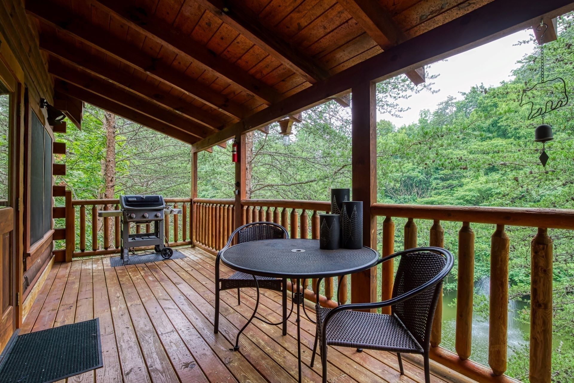 Une terrasse en bois avec une table et des chaises, un barbecue et une vue sur une zone boisée.