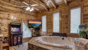 Ein Interieur einer Holzhütte mit einer Steinbadewanne, einem Fernseher und einer Kaffeemaschine.
