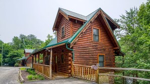 Eine Blockhütte mit Veranda, einem überdachten Gang und einem Schild, das sie als Urlaubsort am See kennzeichnet.