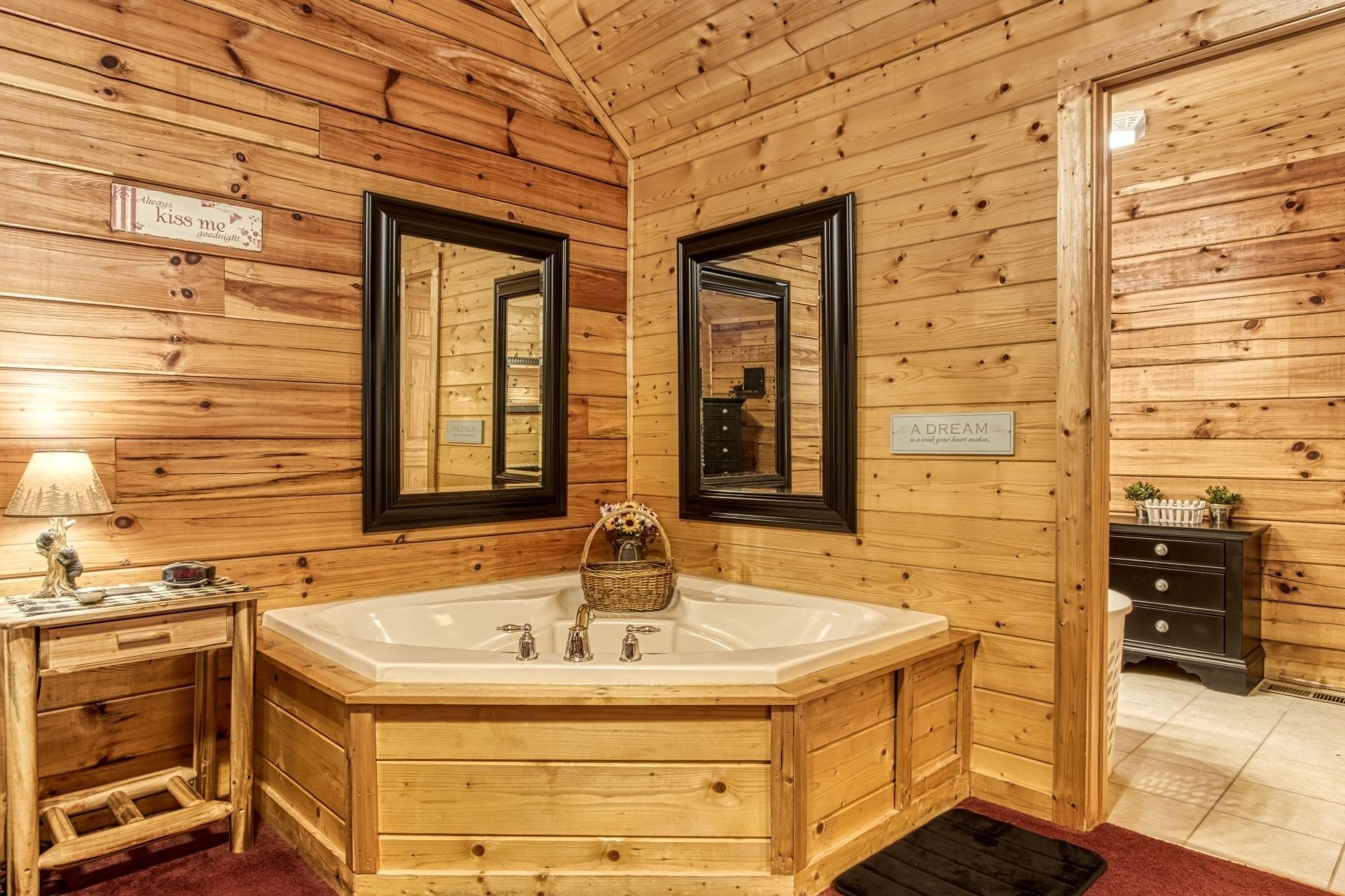 Ein Badezimmer in einer Holzhütte mit einer freistehenden Badewanne, zwei Spiegeln, einem Waschtisch mit Lampe und einem Schild mit der Aufschrift 'A DREAM is a wish your heart makes.'