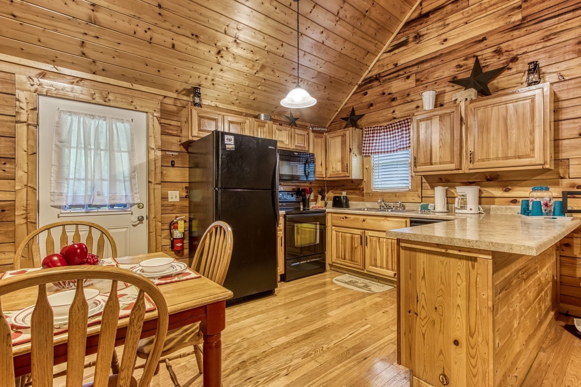 A wooden cabin kitchen with a dining area.