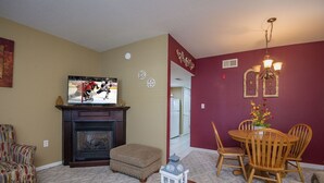 Una sala de estar con chimenea, televisor y comedor con mesa y sillas.