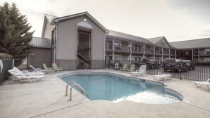 Un hotel con piscina, zona de estar exterior y espacio cubierto.