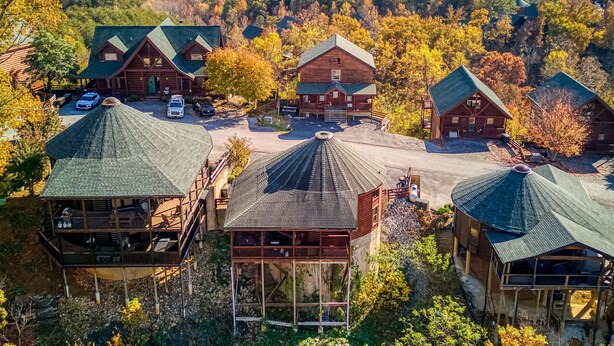 A lodge with multiple cabins, a central building, and a parking area surrounded by autumn foliage and mountains in the background. - Declan's View - Cozy 1 bedroom with Game room and Great Mountain Views! 1 Cabin by RedAwning (Sevierville)
