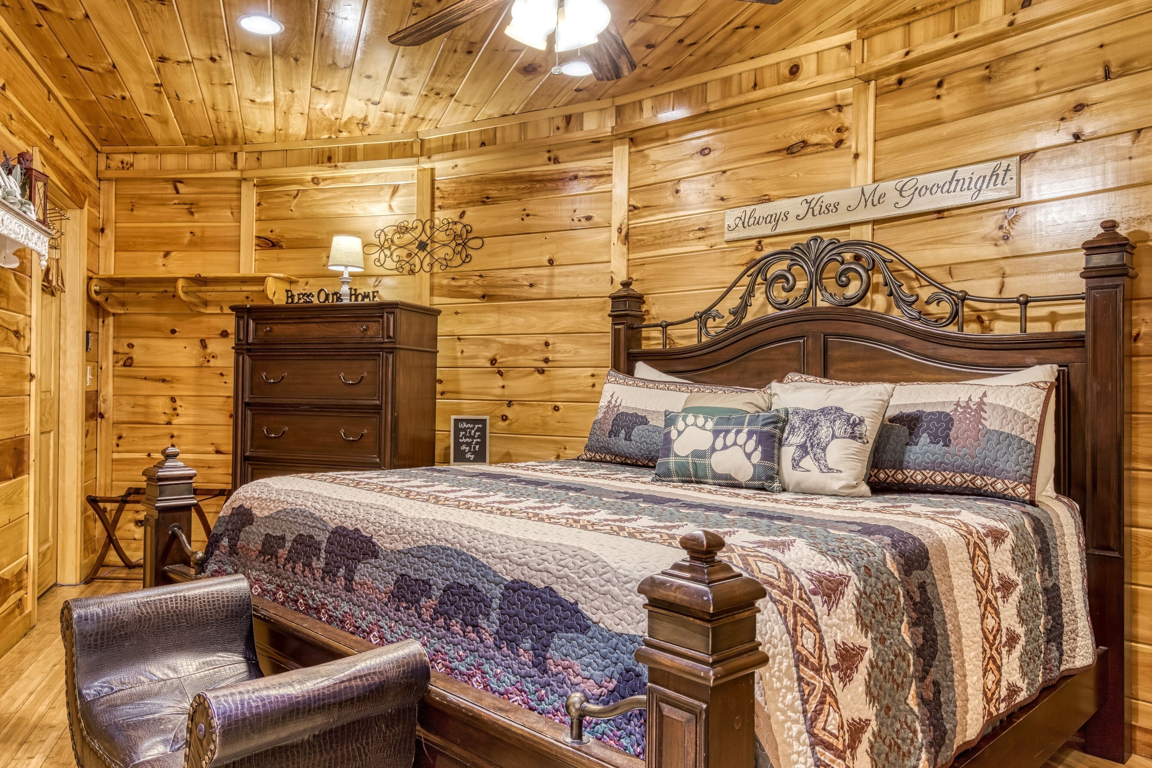 A cozy wooden cabin bedroom with a large bed, a dresser, and a chair.