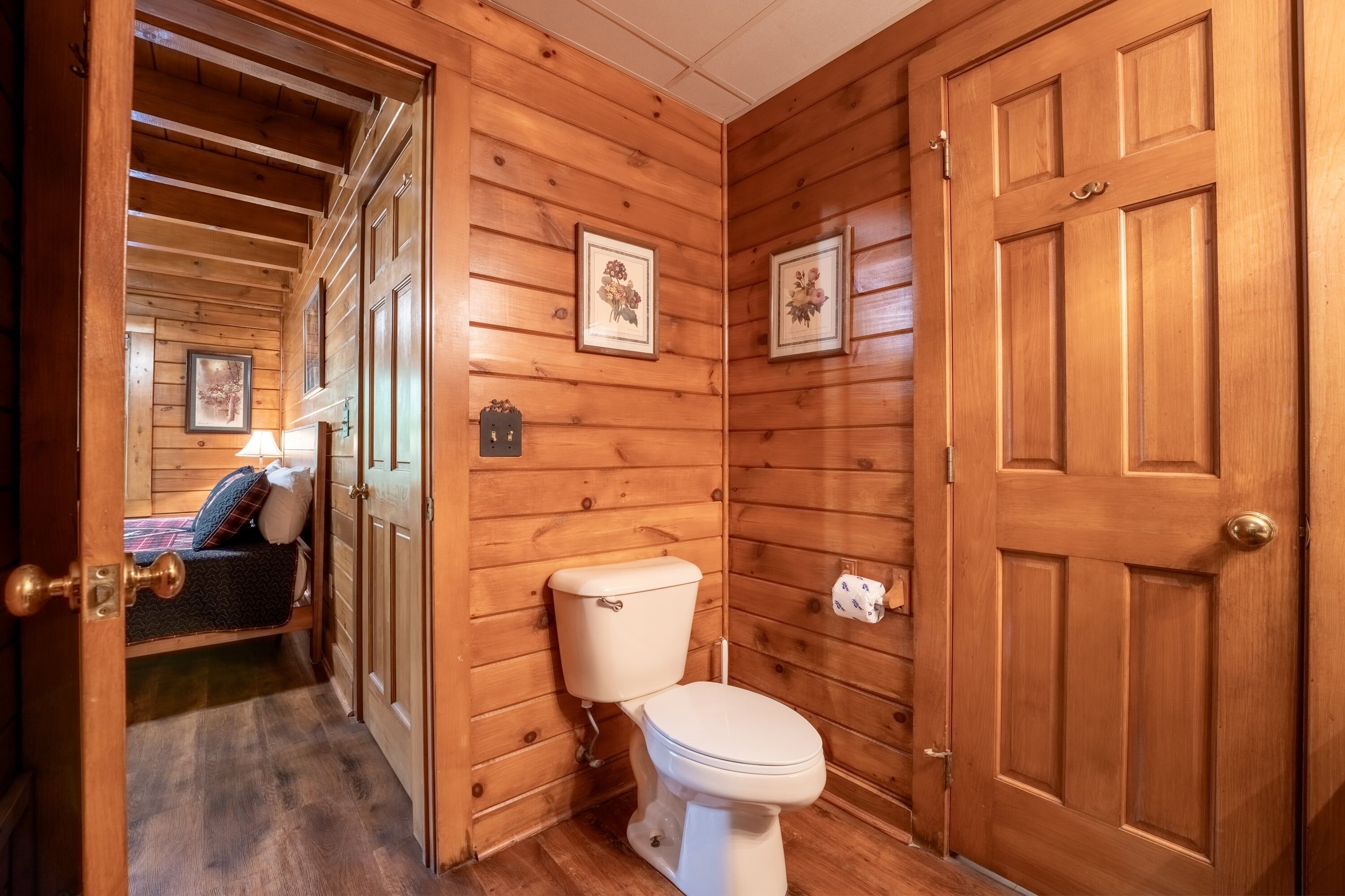 Un bagno con rivestimento in legno, un water, un letto con cuscino e una porta.
