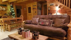 A cozy cabin interior with a wooden dining table, a brown leather couch, and a Christmas tree. - ER246 - The Getaway Great Location - Close To Town! 2 Bedroom Cabin by RedAwning (Pigeon Forge)