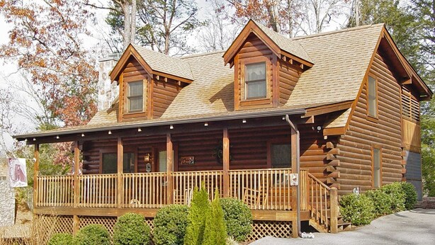 A log cabin with a porch, two chimneys, and a stone foundation. - ER246 - The Getaway Great Location - Close To Town! 2 Bedroom Cabin by RedAwning (Pigeon Forge)