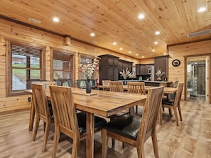 A wooden interior with a dining area, kitchen, and a bathroom with a stone shower. - Ern840 - Splashin' Chalet - Brand New Cabin With Indoor Pool! Great Location! 6 Bedroom Cabin by RedAwning (Pigeon Forge)