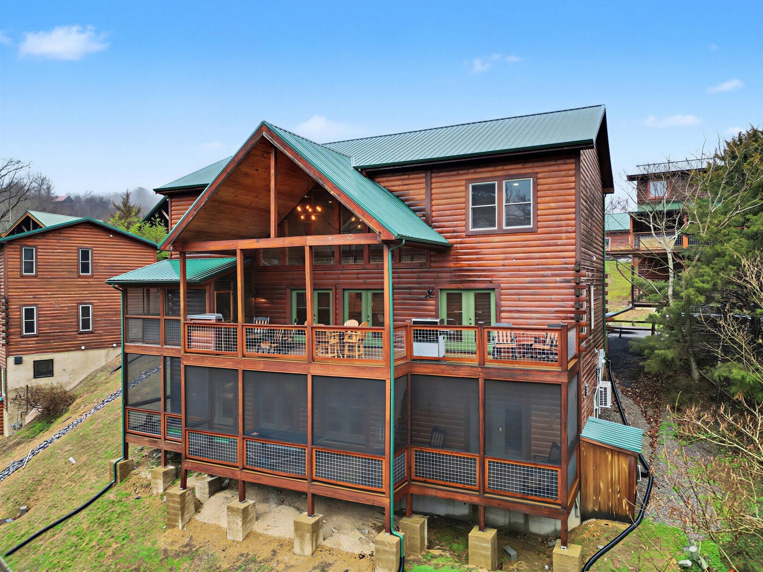 A log cabin with a balcony, multiple windows, and a green roof.