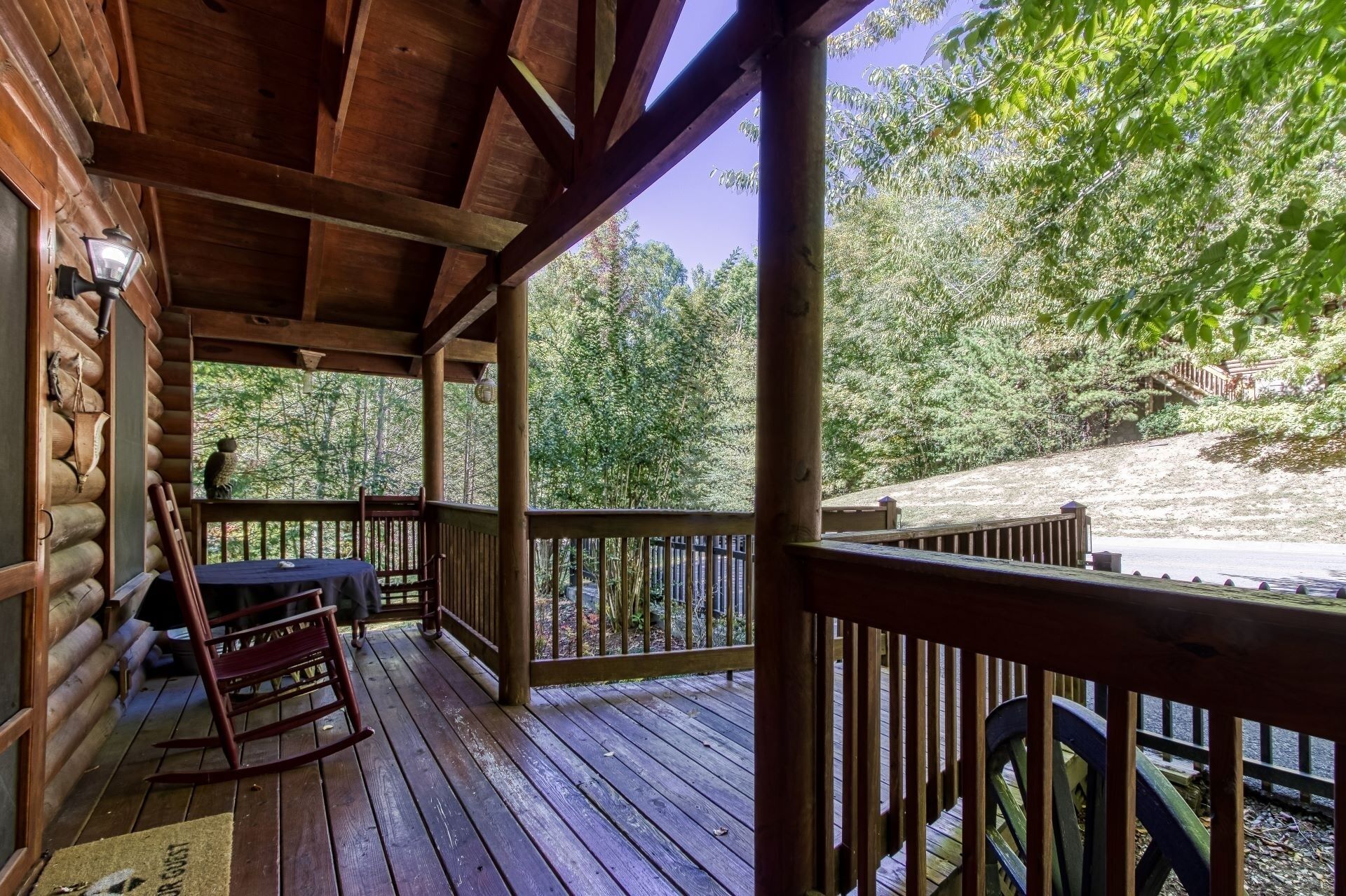 A wooden cabin with a porch, a rocking chair, and a table.