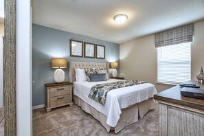 A bedroom with a bed, nightstands, a dresser, and a window with blinds.