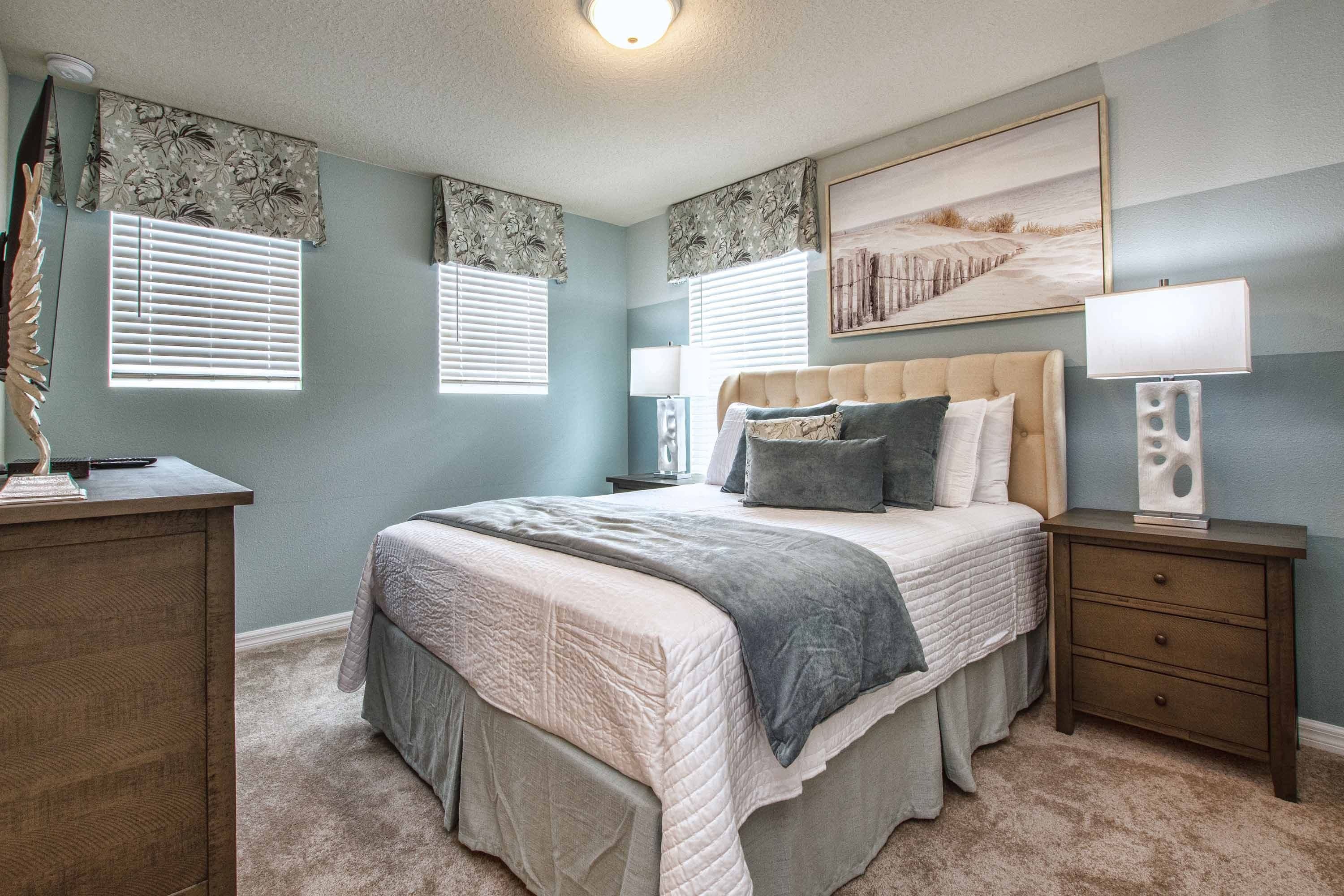 A bedroom with a large bed, bedside tables, a dresser, and a painting on the wall.