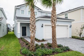 A residential house with a garage, a front door, and two palm trees.