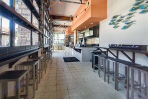 Een restaurant met een lange toonbank, barstoelen en uitzicht door grote ramen.