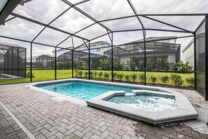 Ein Schwimmbad mit Whirlpool, umgeben von einer überdachten Terrasse mit Blick auf Häuser im Hintergrund.