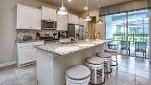 A modern kitchen with white cabinets, granite countertops, and a large island with bar stools.