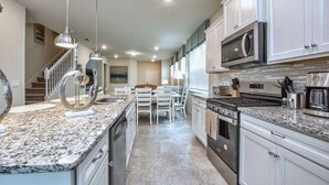 A modern kitchen with granite countertops, stainless steel appliances, and white cabinetry.