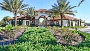 A building with a central arched entrance, surrounded by palm trees and landscaped gardens.