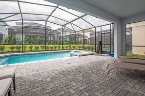 A covered outdoor swimming pool with a hot tub, surrounded by a brick patio and a glass enclosure. - Brand New Family Getaway W/pool & Spa -7049sr 5 Bedroom Home by RedAwning (Davenport)