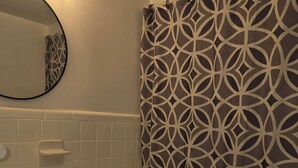 Une salle de bain avec un lavabo blanc, des toilettes et un rideau de douche à motifs géométriques.