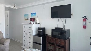 Une chambre d’hôtel équipée d’un lit, d’une commode, d’un four à micro-ondes, d’une machine à café, d’une télévision et d’un extincteur.