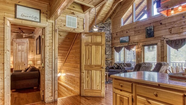 A cozy cabin interior with a wooden interior, a stone wall, a fireplace, and a comfortable seating area. - Ern850 - Simply The Best - Great Location - Close To All The Action! 4 Bedroom Cabin by RedAwning (Pigeon Forge)