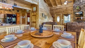 A wooden cabin interior with a dining area, kitchen, and a cozy living space. - Ern850 - Simply The Best - Great Location - Close To All The Action! 4 Bedroom Cabin by RedAwning (Pigeon Forge)