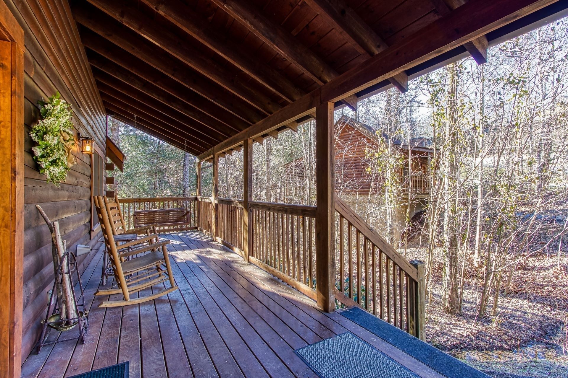 A wooden deck with a bench and a rocking chair, overlooking a forested area.