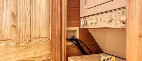 A laundry room with wooden cabinets and a washing machine.