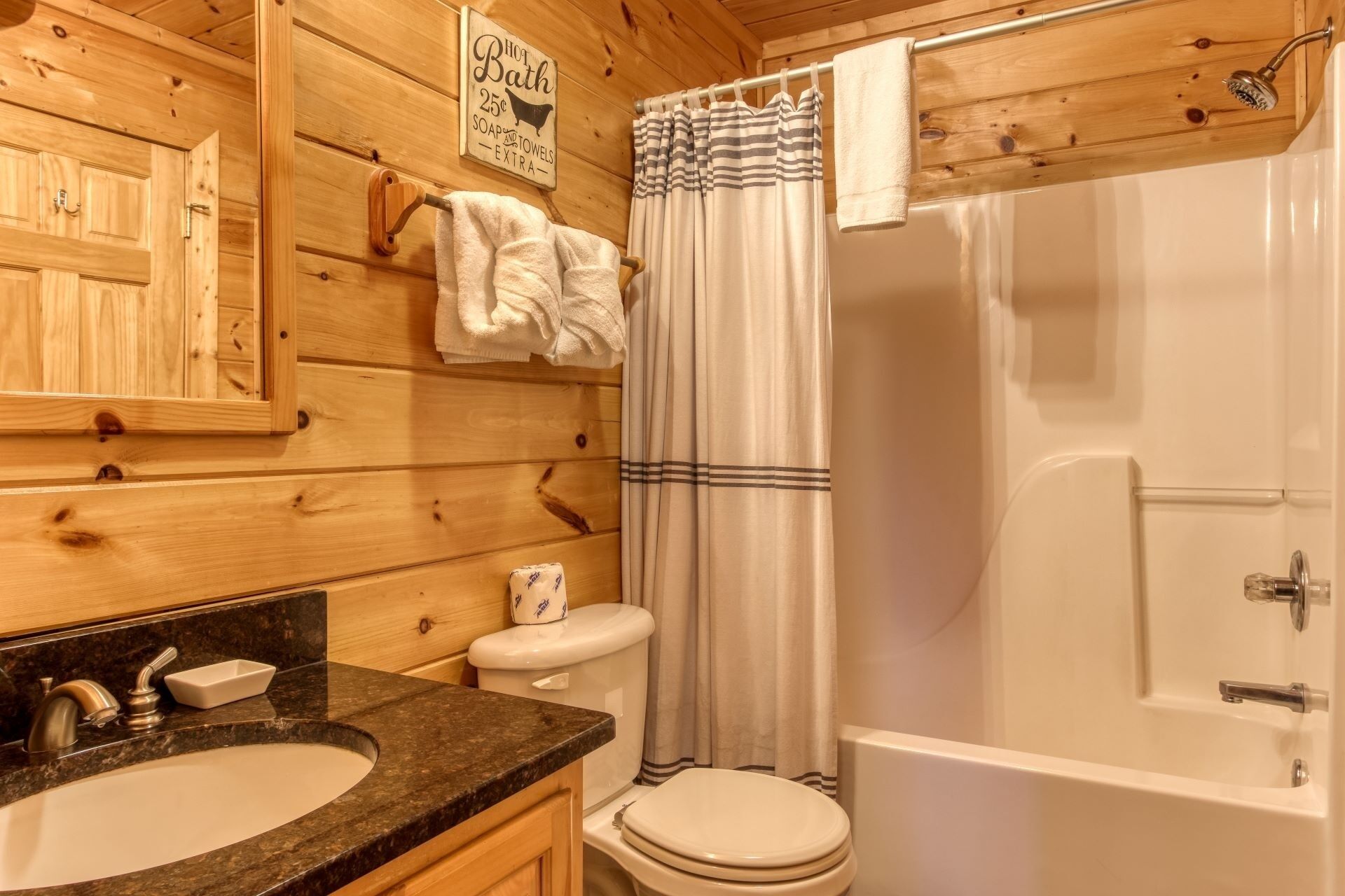 A wooden cabin bathroom with a sink, toilet, and bathtub.