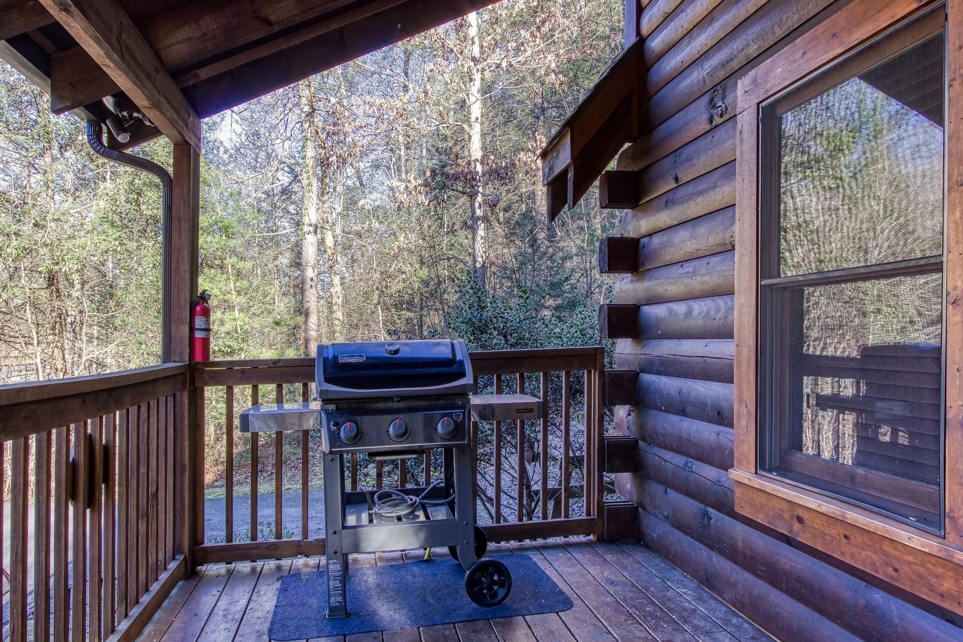 A wooden deck with a barbecue grill and a fire extinguisher.
