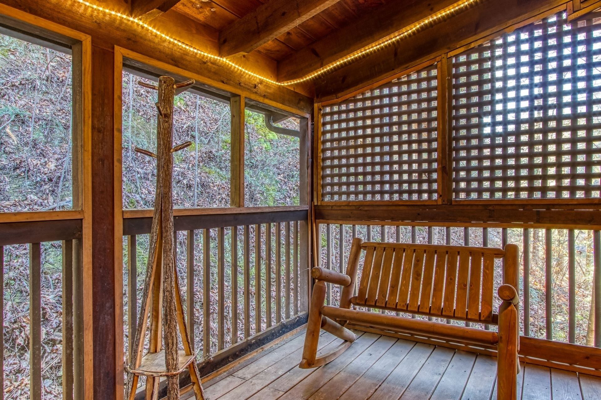 A wooden deck with a bench and a tree stump ladder.