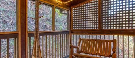 Una terraza de madera con un banco y una escalera de tocón de árbol.