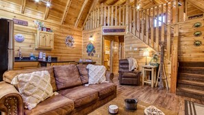 A cozy log cabin interior with a living room, a kitchen, and a staircase. - Er260- Magical Moments Great Location- Close To Town 1 Bedroom Cabin by RedAwning (Pigeon Forge)