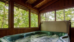 Ein Whirlpool mit Blick auf Bäume durch große Fenster.