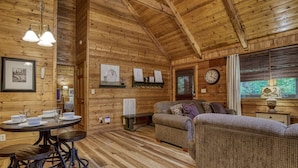 Ein gemütliches Blockhaus-Interieur mit Essbereich, einer Couch und einer Wanduhr.