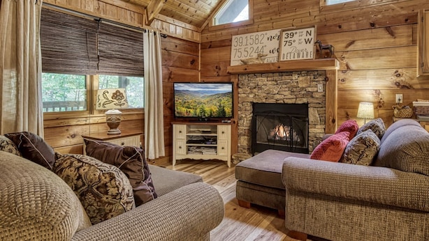 Ein gemütliches Blockhaus mit Kamin, Holzwänden, Fernseher und bequemen Sitzmöglichkeiten.