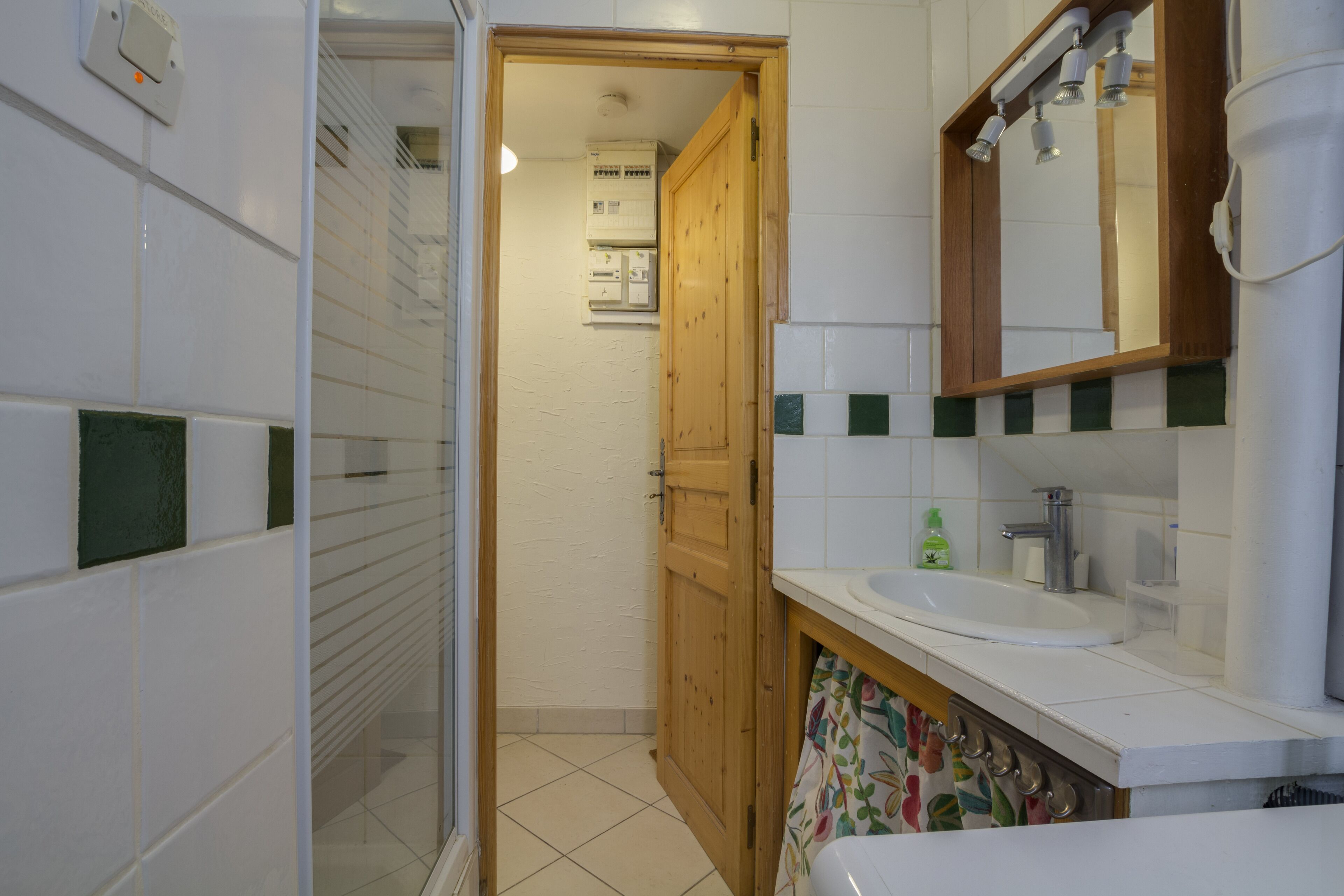 A bathroom with a wooden door, a white sink, and a mirror above it.