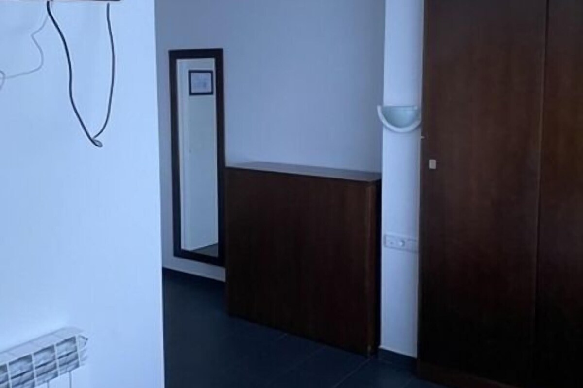 Habitación de hotel con una cama, televisión en la pared, armario y espejo.